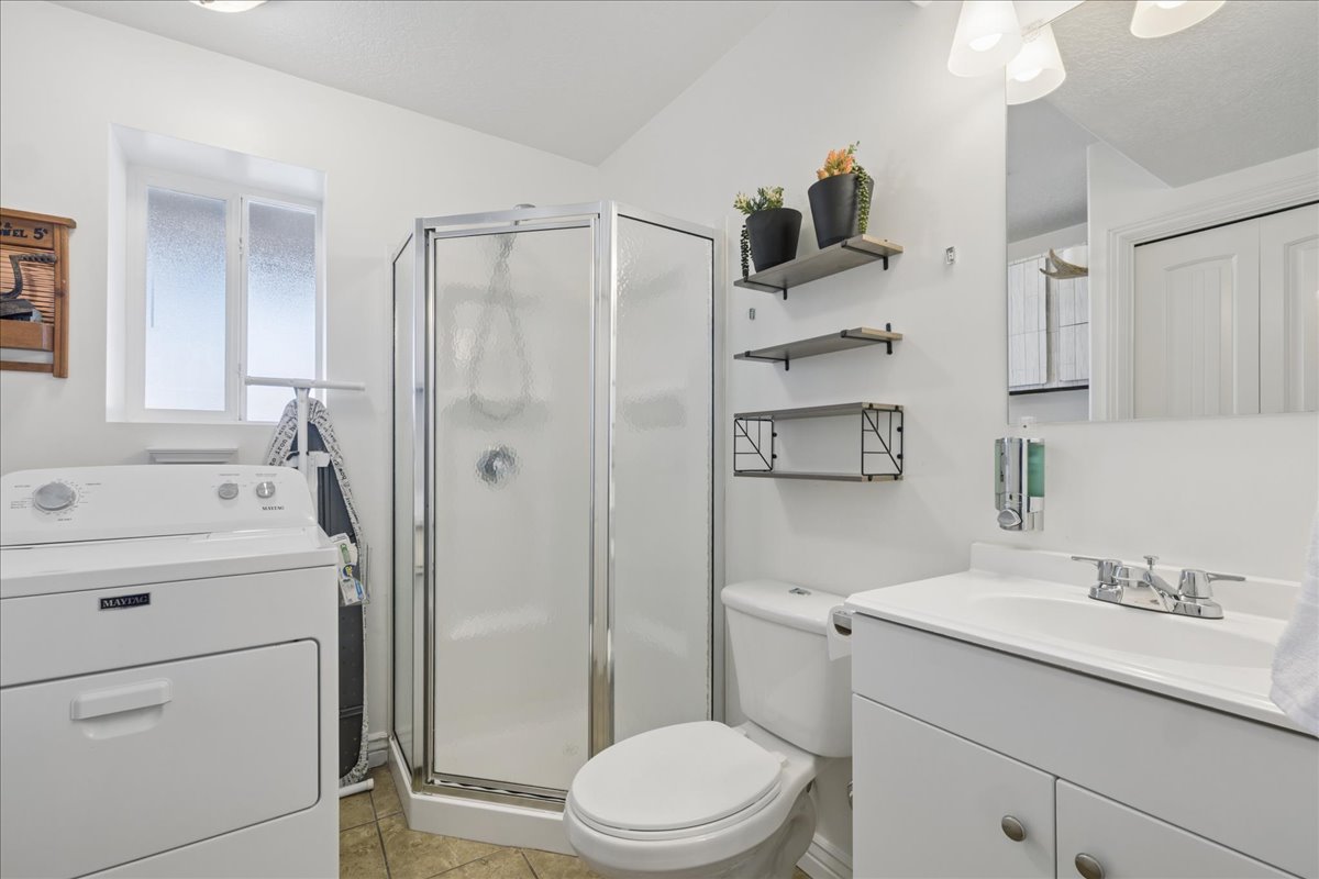 Bathroom featuring a glass-enclosed shower, white vanity with integrated sink, and wood-finish flooring