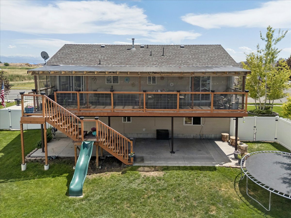 Rear exterior featuring a two-story design with a screened-in upper deck and an open-air lower patio
