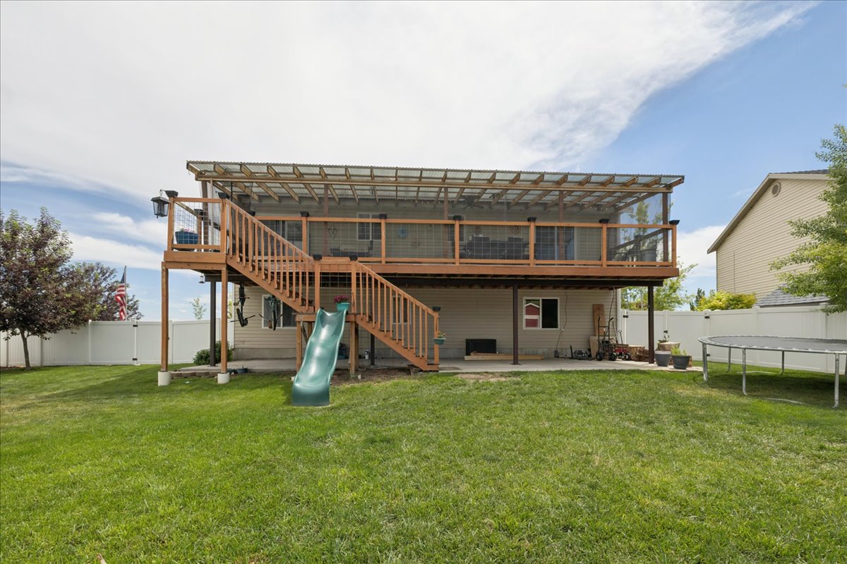 Expansive fenced backyard featuring a two-story wood deck with screened upper level, and a lower-level concrete patio
