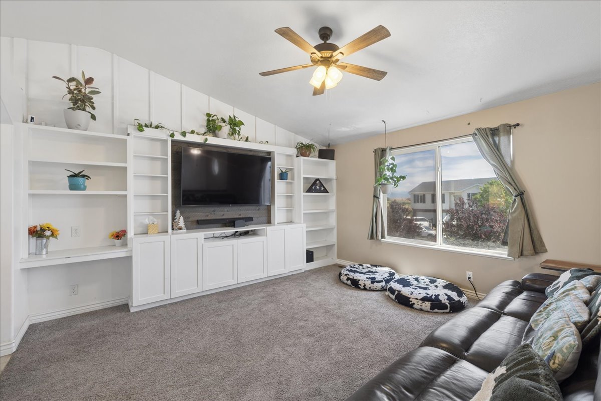 Living area featuring a spacious built-in entertainment center, vaulted ceilings with wood paneling, and neutral-toned carpeting