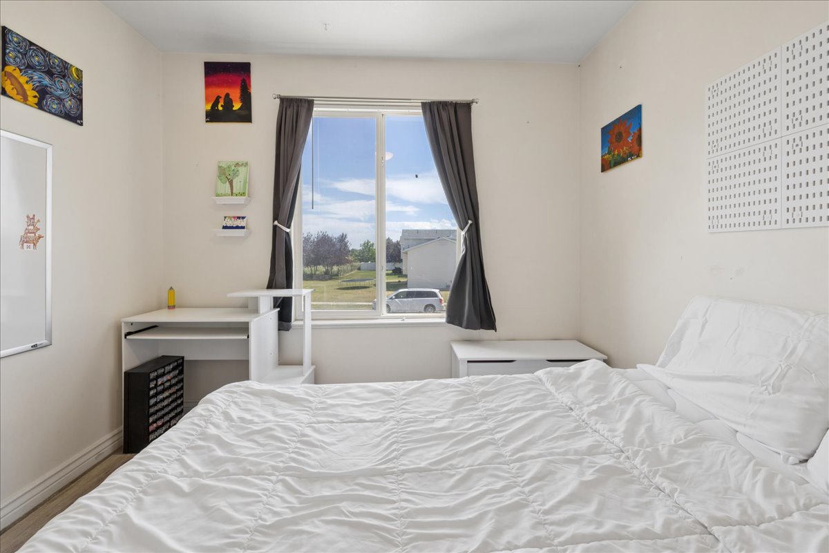 Bright interior space featuring a window with dark drapes, light-colored walls, and wood-finish flooring