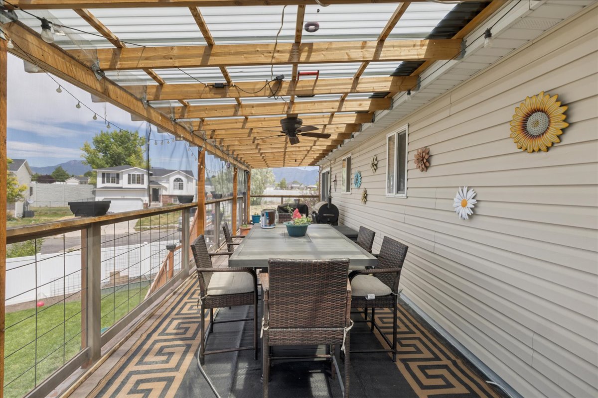 Expansive covered deck featuring a transparent roof, wood-finish support beams, string lighting, and a ceiling fan