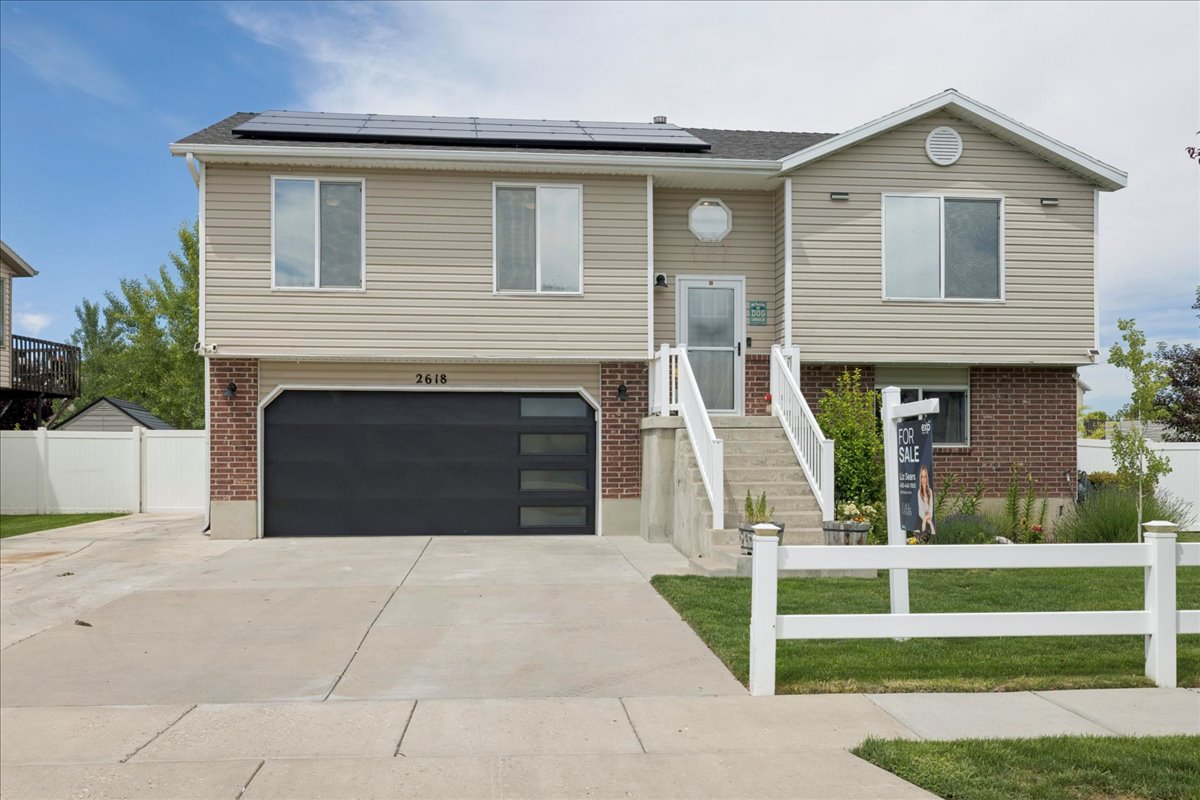 Two-story residence featuring light-toned siding, brick accents, and a dark garage door with horizontal window panels