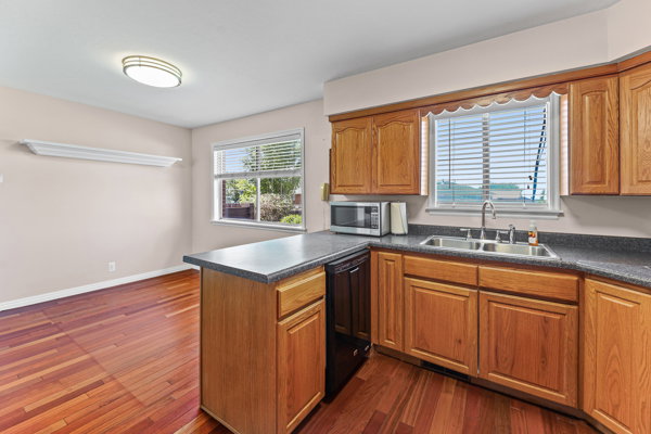 Kitchen featuring wood-finish flooring, natural wood cabinetry, a double basin sink, and laminate countertops