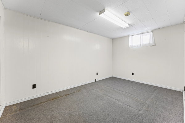 Carpeted room featuring white paneling walls and a drop ceiling with fluorescent lighting