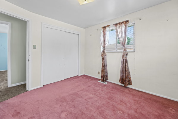 Room featuring wall-to-wall carpeting, dual windows, and a built-in closet with sliding doors