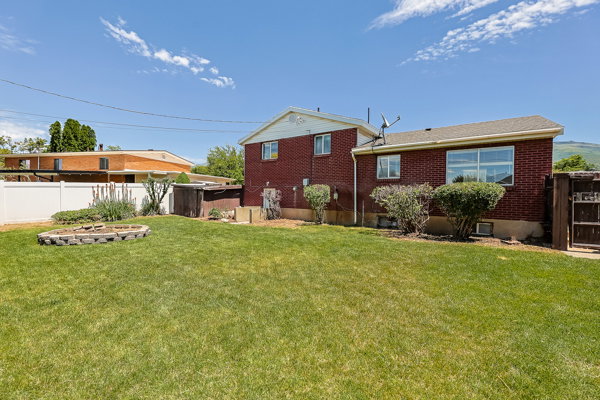 Expansive green lawn with a structured garden bed and a white vinyl fence