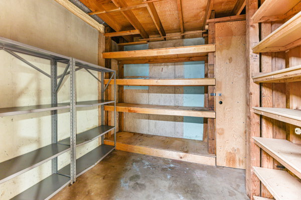 Utility room with exposed wooden ceiling joists, concrete flooring, and bare concrete walls