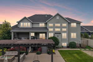 Rear exterior featuring a covered patio, multi-level windows, a dark shingle roof, and a wood pergola over a patio