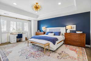 Spacious bedroom featuring a tray ceiling, recessed lighting, and a modern sputnik chandelier