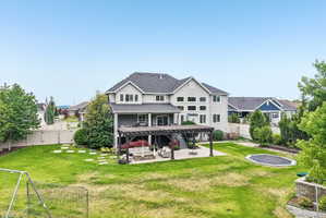 Spacious rear exterior featuring a two-story residence with multiple windows, a covered patio with a dark wood pergola, and a concrete patio space