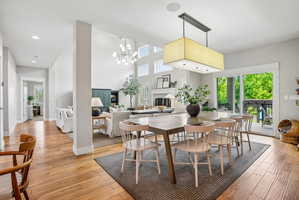 Dining area featuring a contemporary rectangular chandelier, wood-finish flooring, and direct access to an outdoor deck