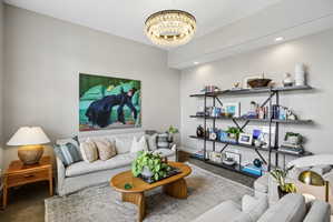 Living area featuring a crystal chandelier, recessed lighting, and a multi-tiered open shelving unit