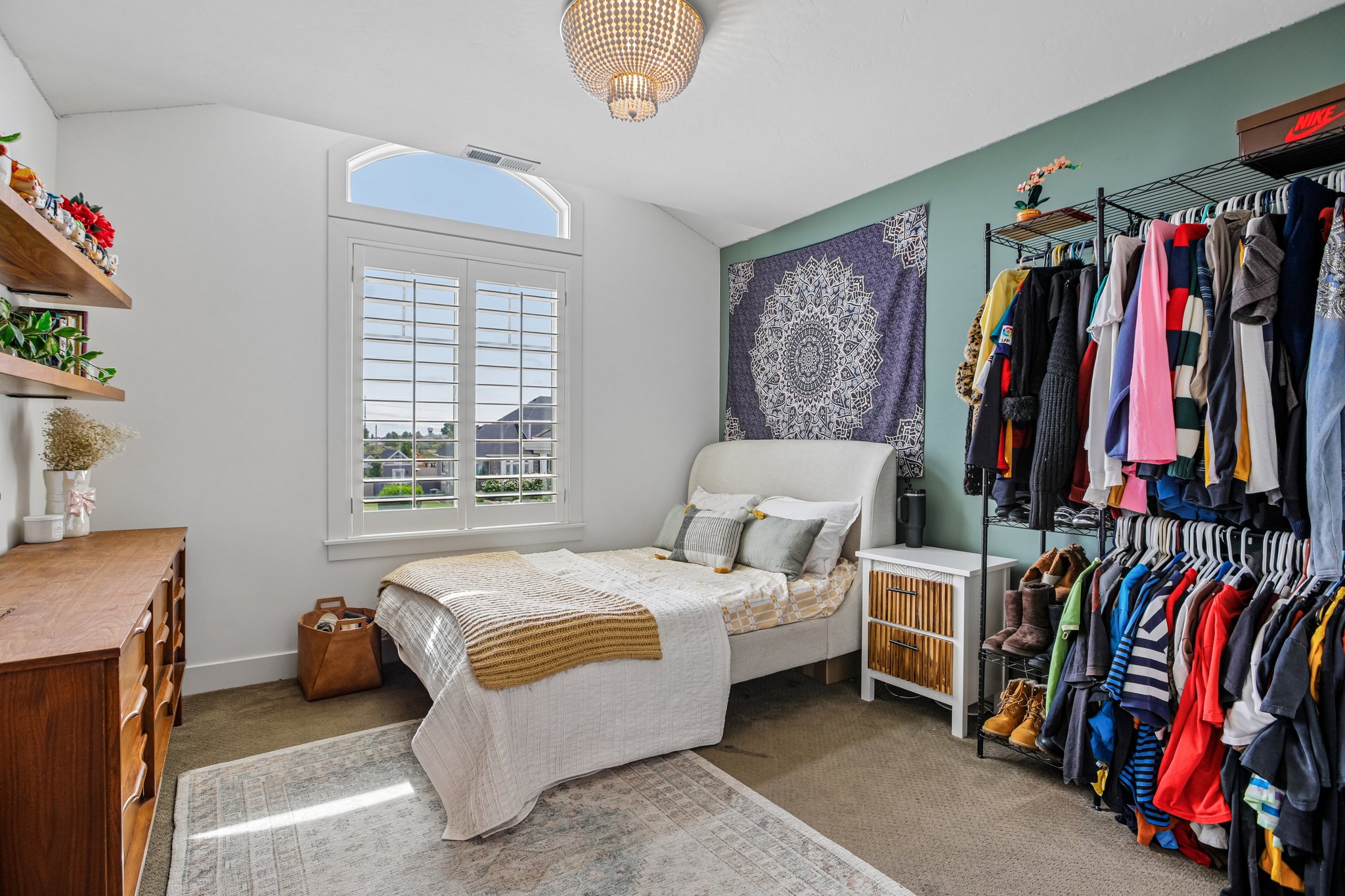 Vaulted ceiling with an arched window, plantation shutters, and a decorative ceiling fixture