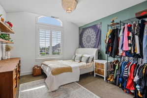 Vaulted ceiling with an arched window, plantation shutters, and a decorative ceiling fixture