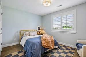 Room featuring a single window with white plantation shutters, light blue walls, and a ceiling-mounted drum light fixture