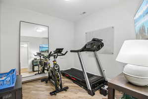 Versatile room featuring wood-finish flooring, recessed lighting, and a full-length mirror
