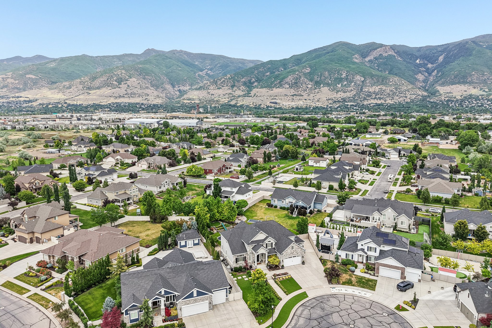 Aerial perspective of a residential neighborhood with varied architectural styles, manicured lawns, and mature trees