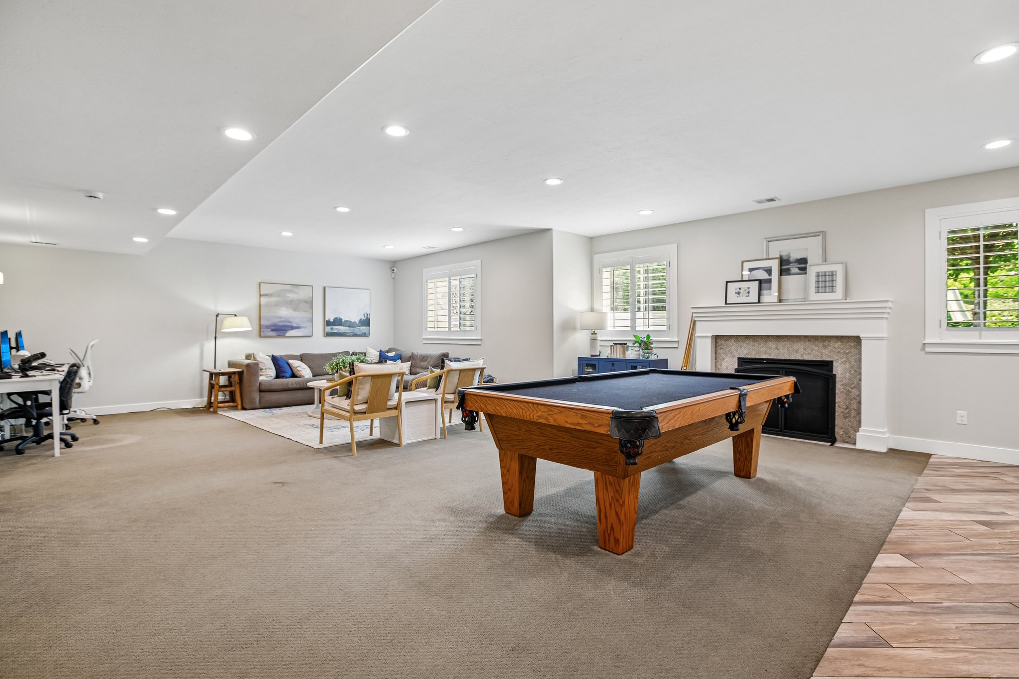 Spacious room featuring recessed lighting and a fireplace with a white mantel and stone surround