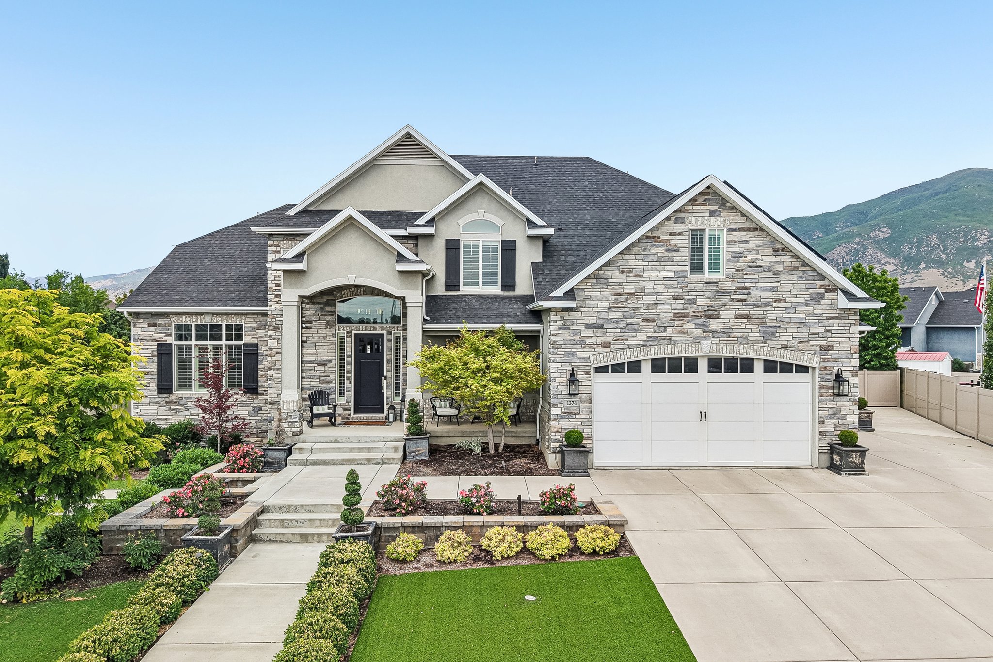 Stately residence featuring a stone and stucco exterior, arched portico entry, and a prominent two-car garage with arched windows