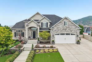 Stately residence featuring a stone and stucco exterior, arched portico entry, and a prominent two-car garage with arched windows