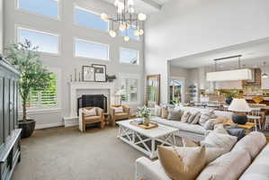 Double-height living space featuring extensive upper-level transom windows, a central chandelier, and a fireplace with a decorative tile surround and mantel