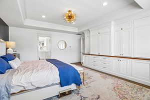 Built-in cabinetry with wood-finish countertop, recessed lighting, and tray ceiling with a contemporary light fixture