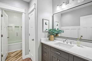 Bathroom featuring a rectangular undermount sink, a stone countertop, a large framed mirror, and a gray vanity with chrome hardware