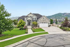 Stone and siding exterior with a prominent arched entry, two-car garage, and a steeply pitched roofline