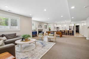 Open-concept living area featuring recessed lighting, plantation shutters, a kitchen island with pendant lighting, stainless steel appliances, and wood-finish flooring