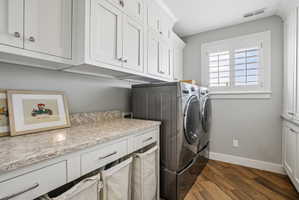 Laundry area featuring wood-finish flooring, white shaker-style cabinetry, and light-toned countertops
