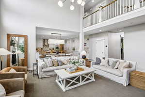 Two-story living area with high ceilings, an upper-level balcony with white balusters, and a contemporary multi-globe chandelier