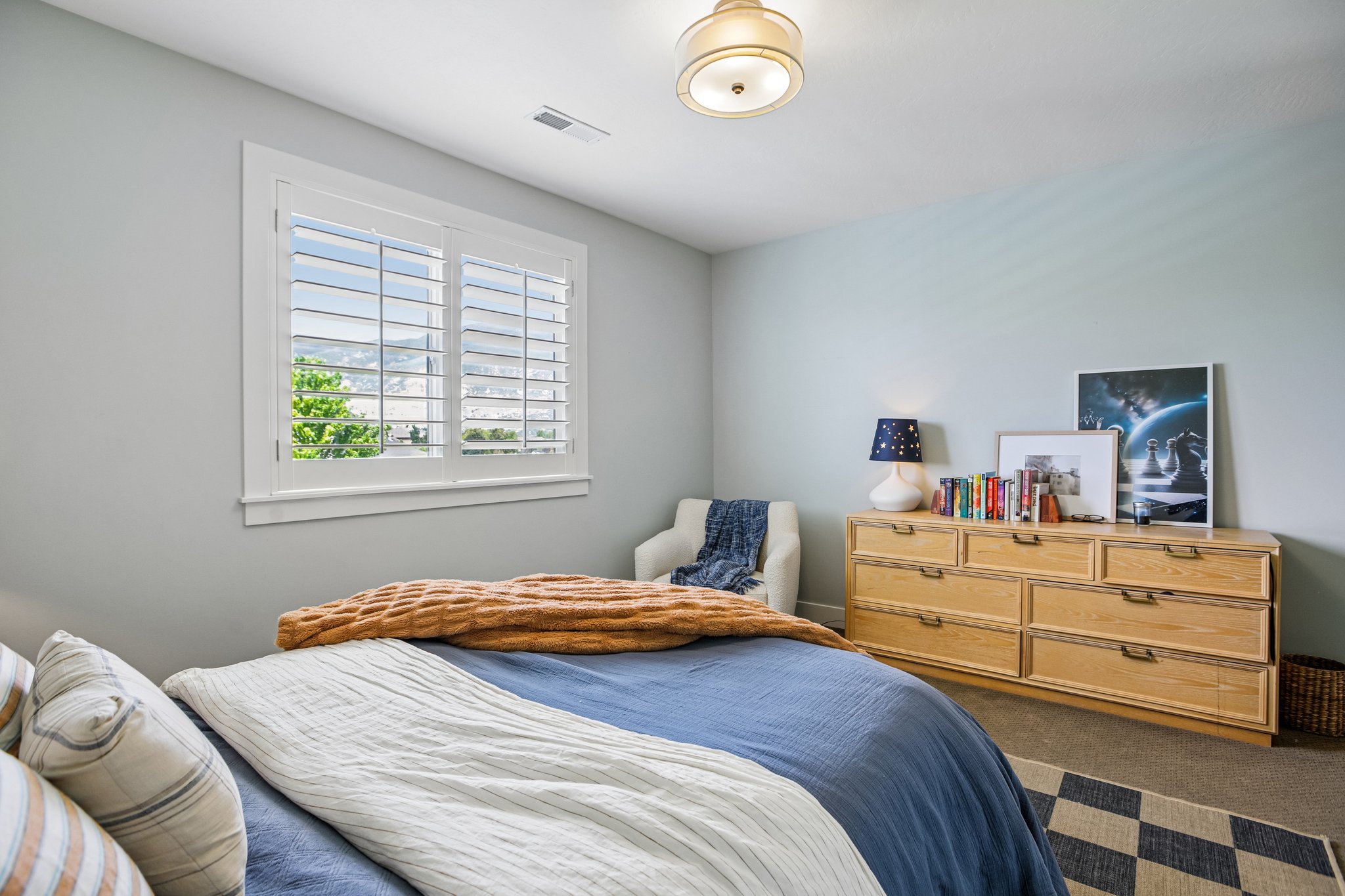 Bright room featuring a window with white louvered shutters, light-toned walls, and a semi-flush mount ceiling fixture