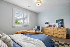 Bright room featuring a window with white louvered shutters, light-toned walls, and a semi-flush mount ceiling fixture
