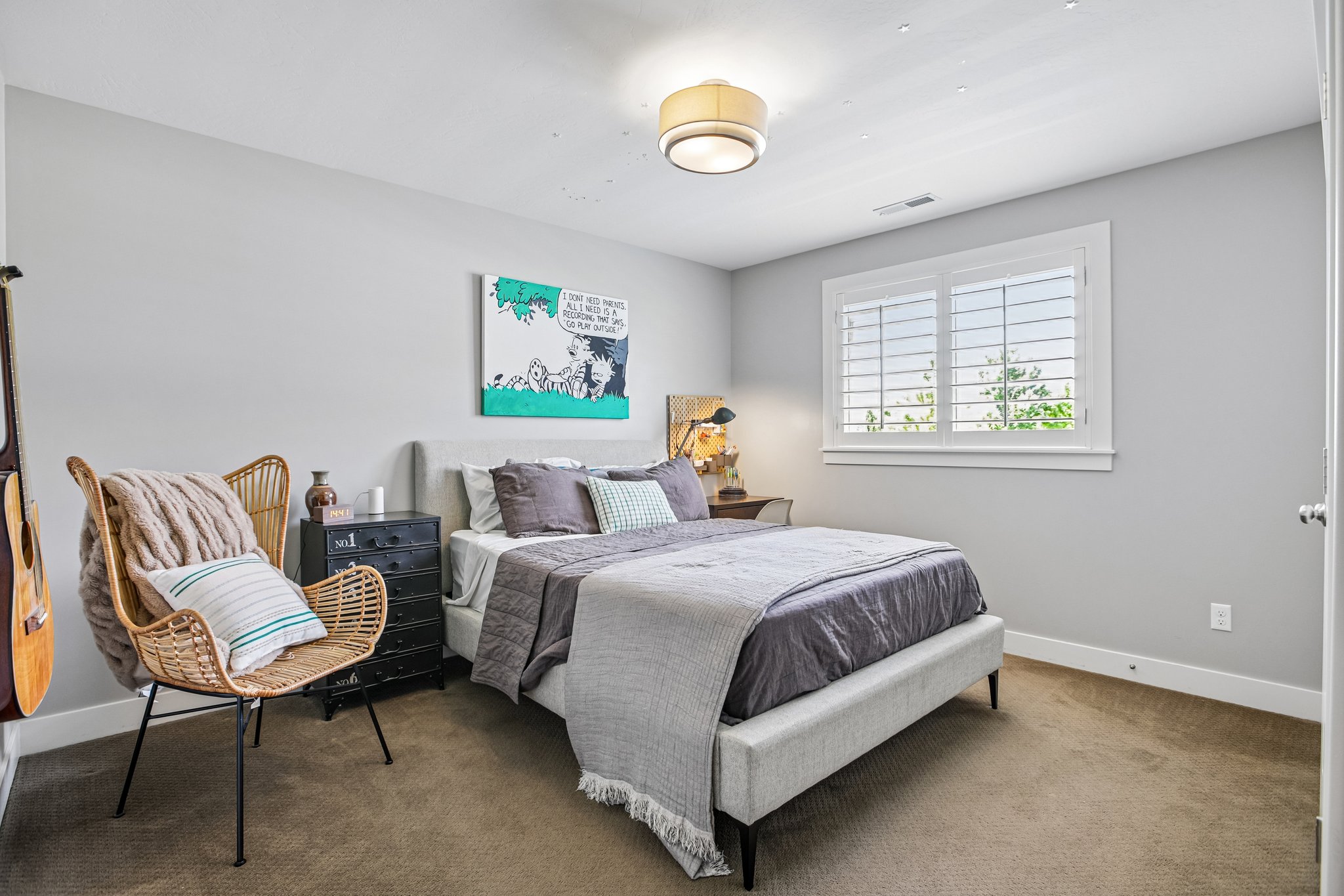 Carpeted bedroom featuring a window with white plantation shutters, a contemporary flush-mount ceiling light, and ample natural light