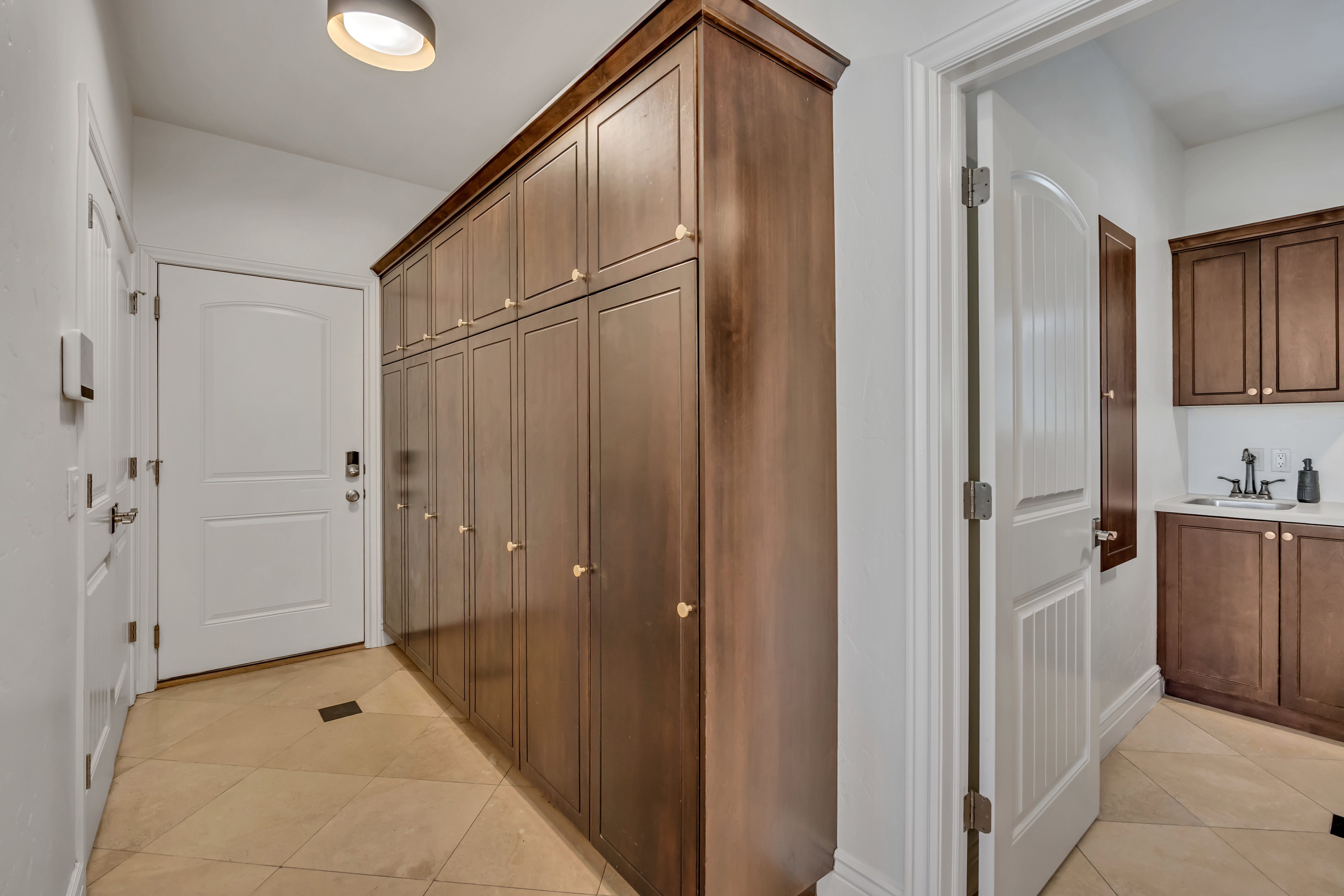 Extensive built-in wood cabinetry with brass hardware, tile flooring, and overhead lighting