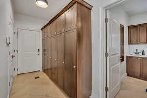 Extensive built-in wood cabinetry with brass hardware, tile flooring, and overhead lighting