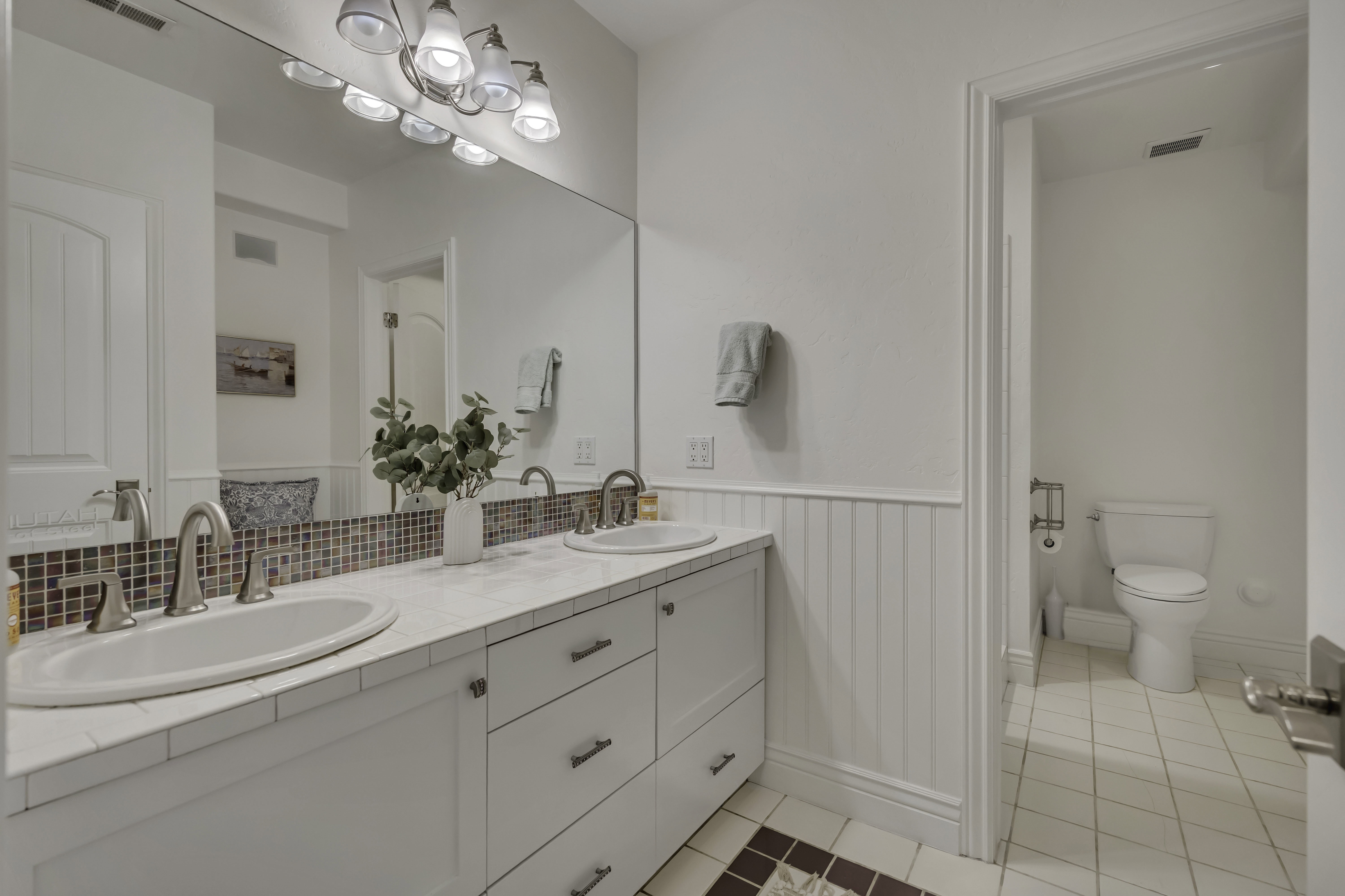Bathroom vanity featuring dual under-mount sinks, brushed nickel fixtures, and a tile countertop