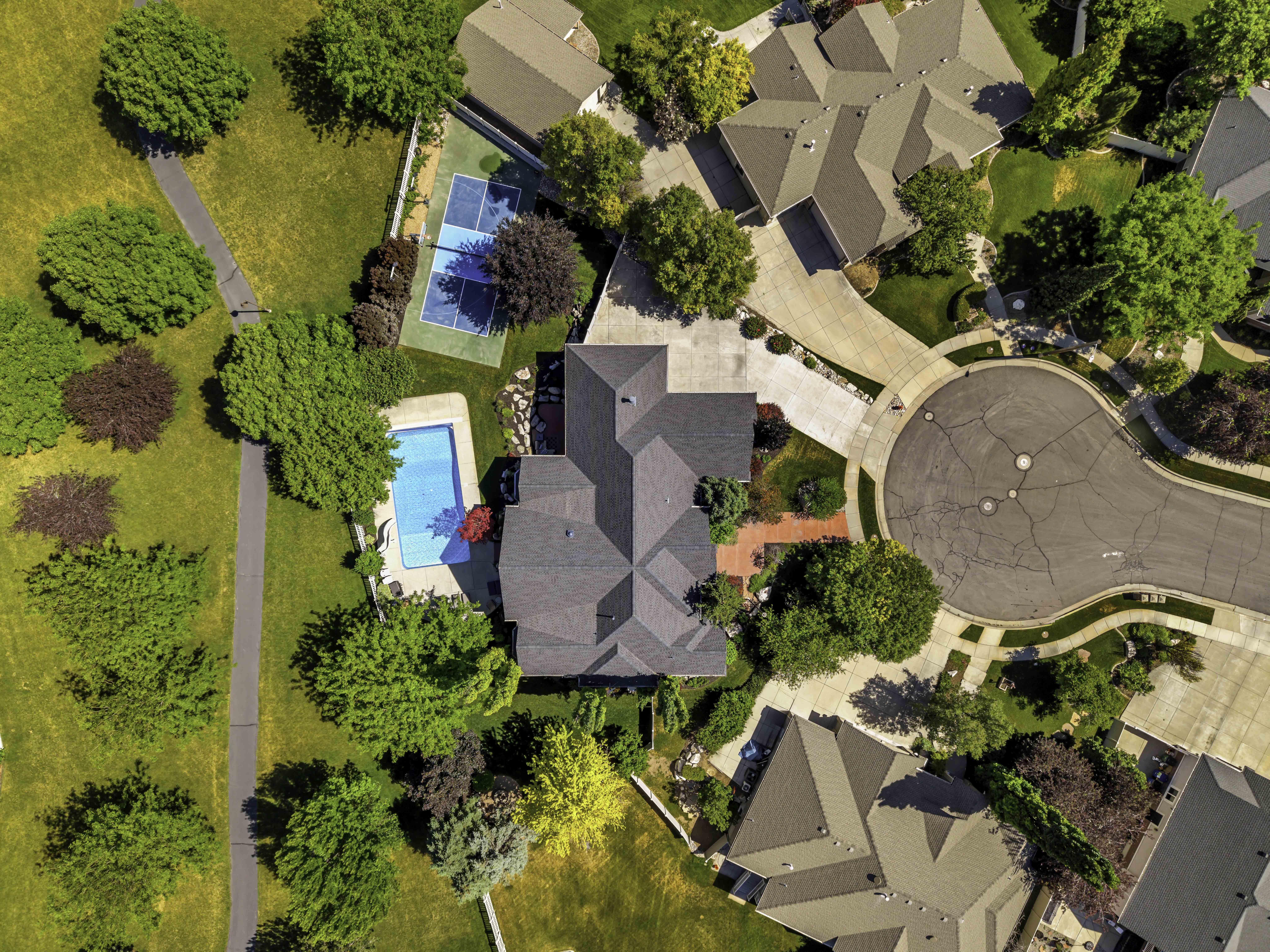 Expansive property featuring a private swimming pool, a dedicated sports court, mature landscaping, a cul-de-sac street, and a multi-gabled roofline