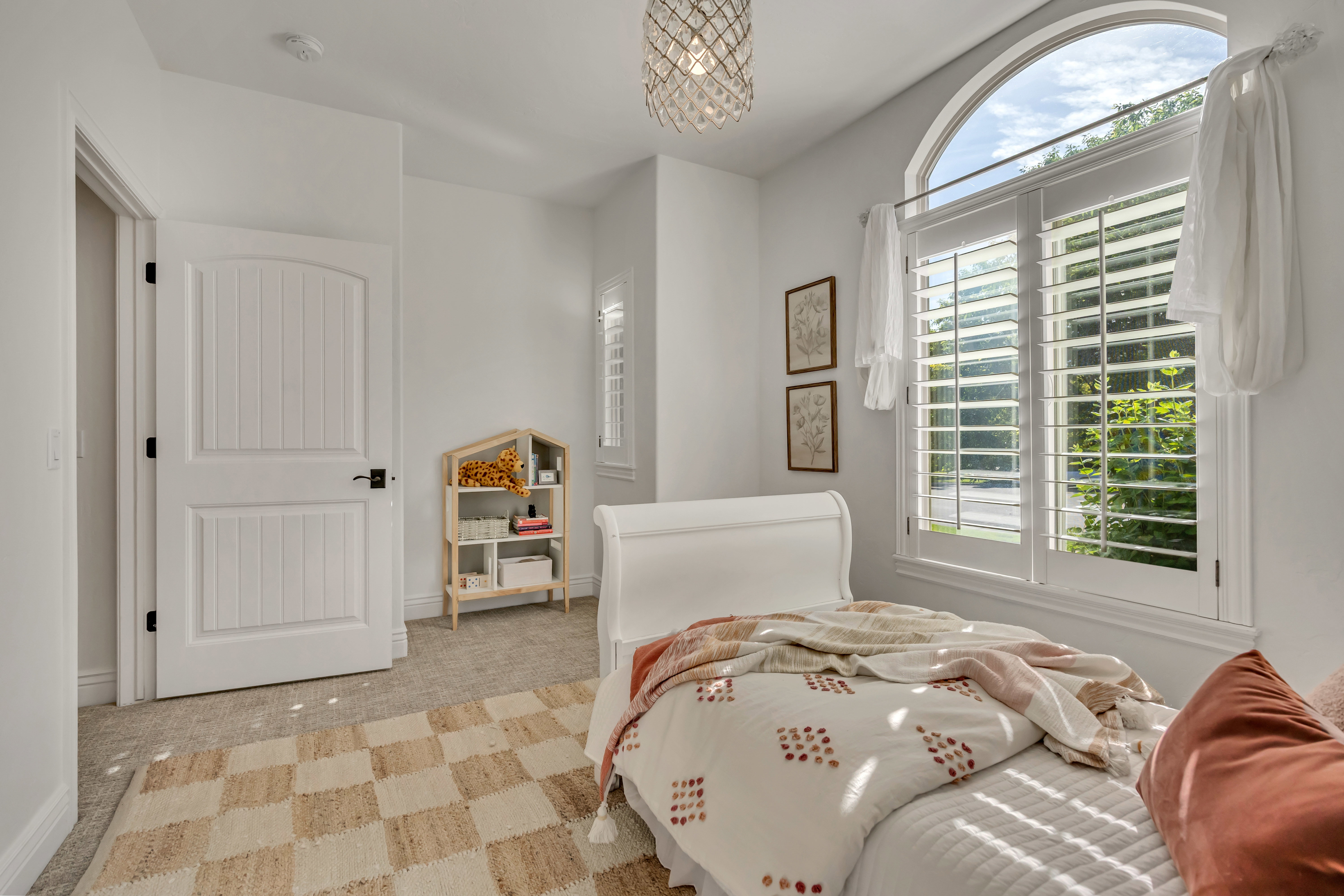 Arched window featuring interior plantation shutters and a crystal chandelier