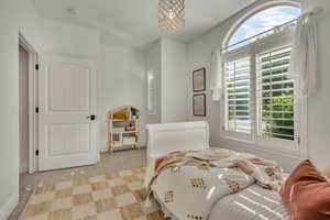 Arched window featuring interior plantation shutters and a crystal chandelier