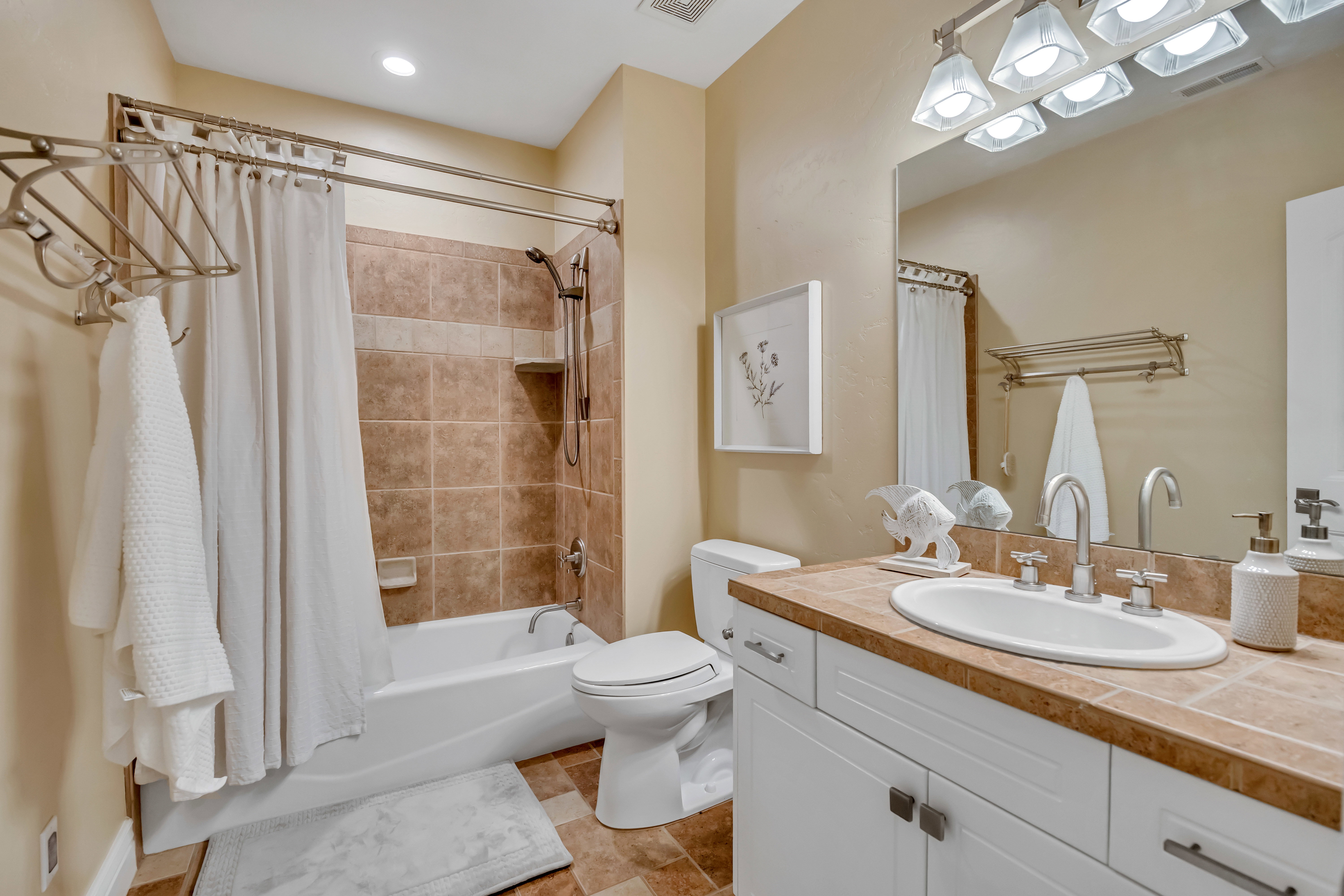 Bathroom featuring a white vanity with cabinet storage, an integrated sink, and a tiled countertop
