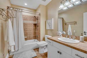 Bathroom featuring a white vanity with cabinet storage, an integrated sink, and a tiled countertop