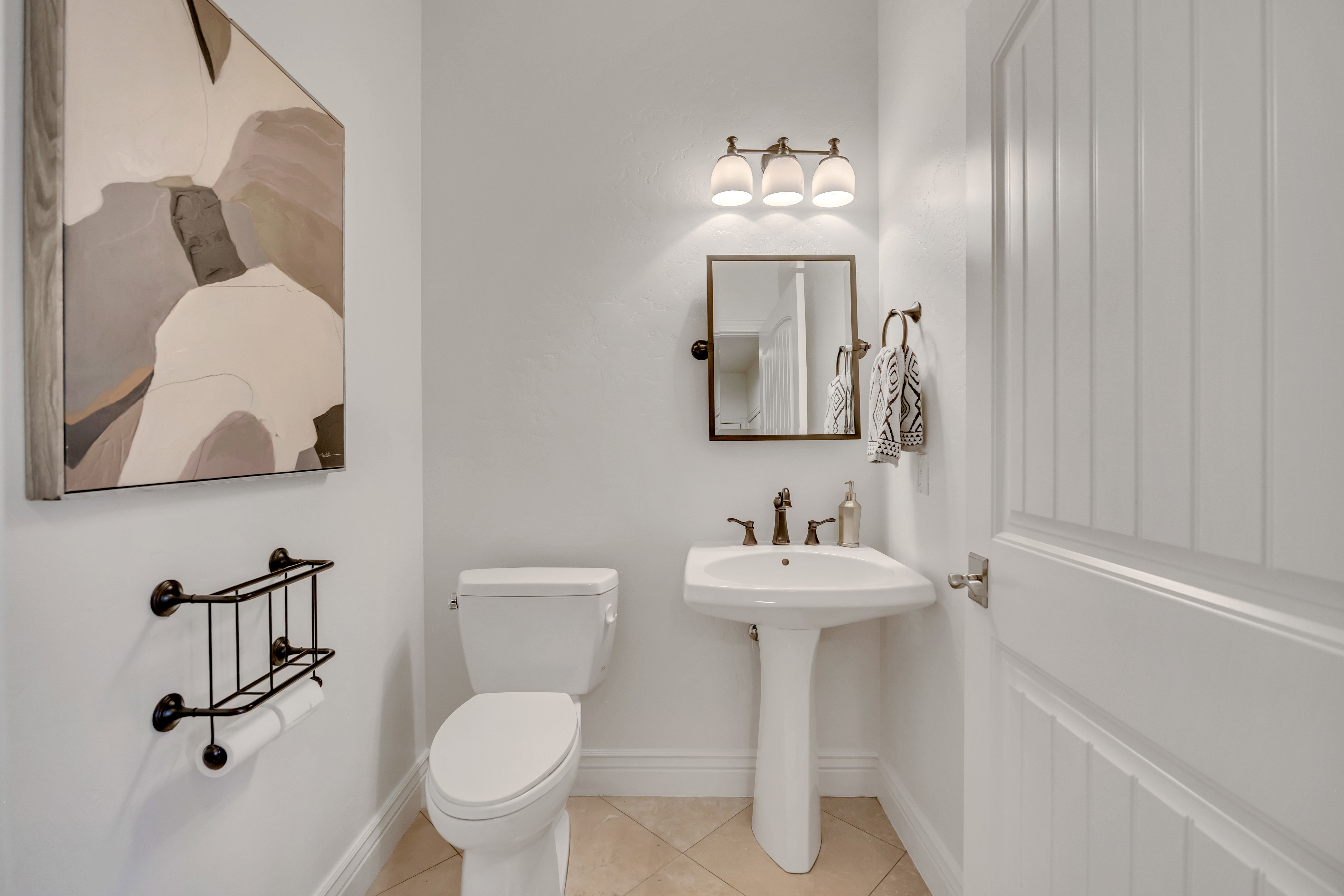 Pedestal sink with bronze-finish faucet, mirror, and coordinating vanity light fixture