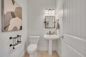 Pedestal sink with bronze-finish faucet, mirror, and coordinating vanity light fixture