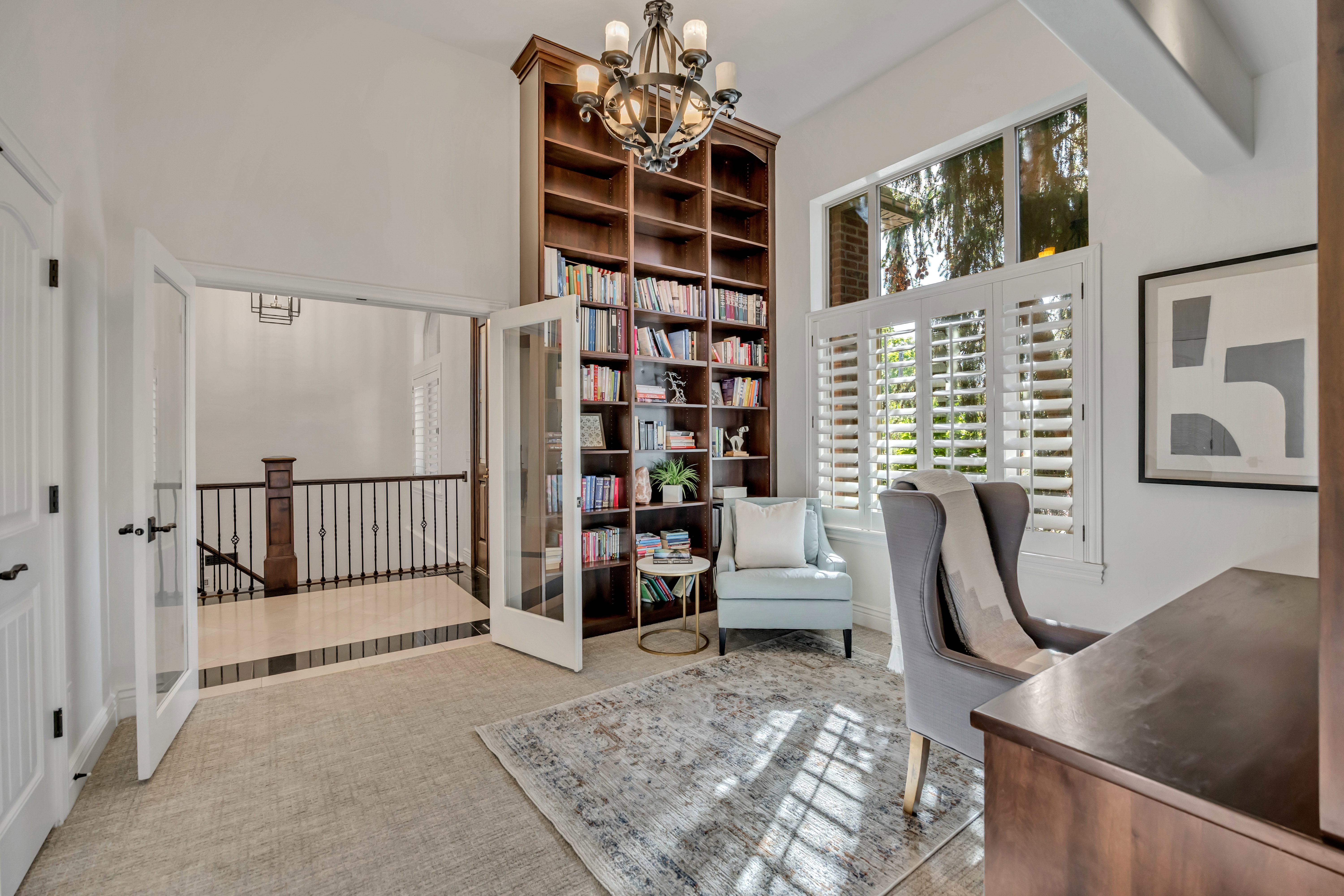 Room featuring extensive custom built-in shelving, glass French doors, and plantation shutters