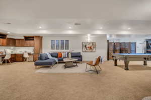 Spacious recreational room featuring a built-in cabinetry desk area, a window with plantation shutters, recessed lighting, and carpet flooring