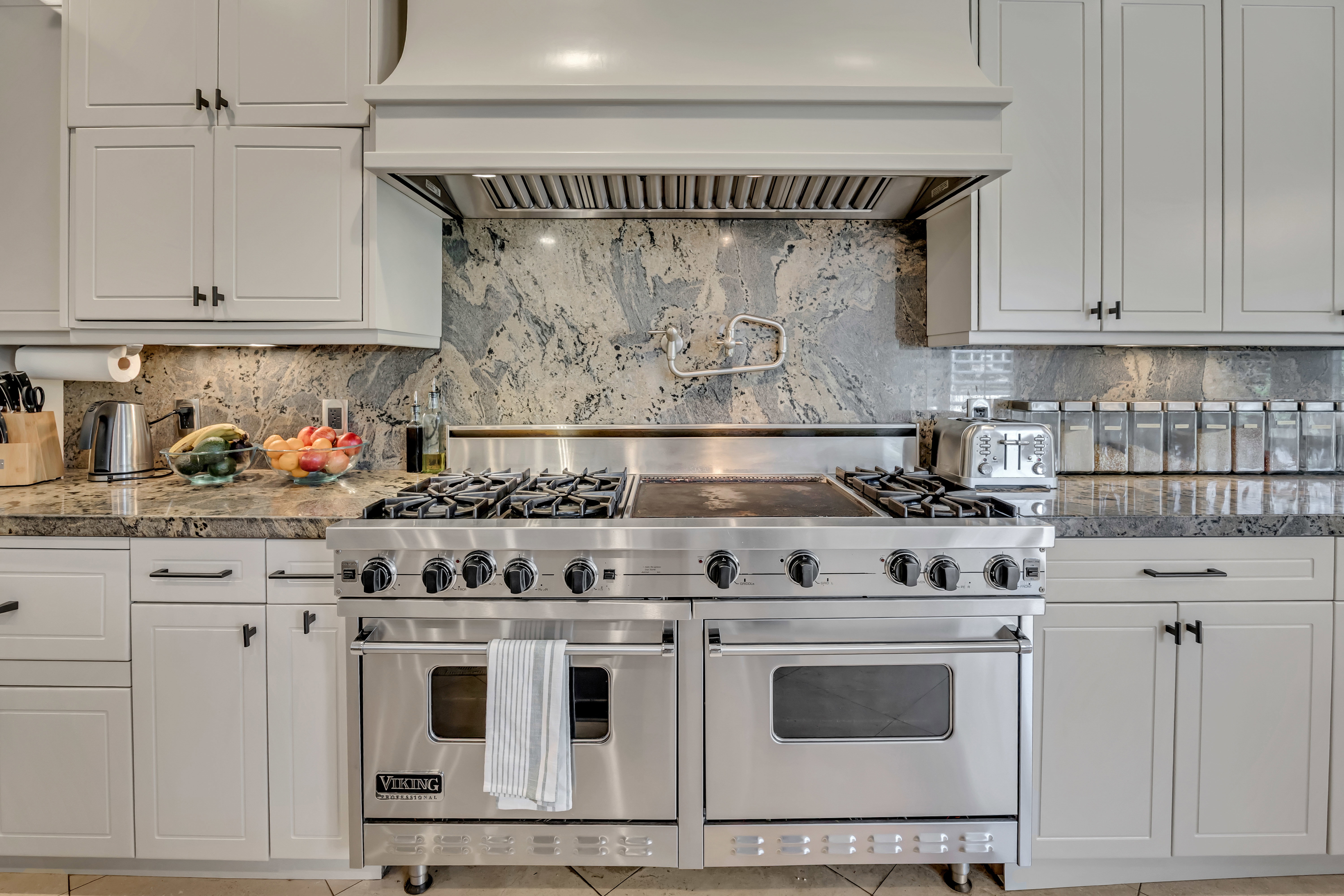Professional-grade stainless steel range with griddle, flanked by light-toned cabinetry and granite countertops
