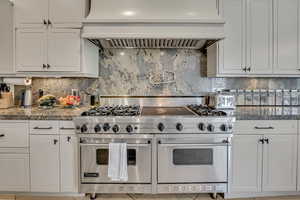 Professional-grade stainless steel range with griddle, flanked by light-toned cabinetry and granite countertops