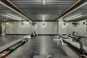 Spacious room featuring floor-to-ceiling mirrors, a durable rubber floor, and exposed industrial-style ceiling with integrated lighting